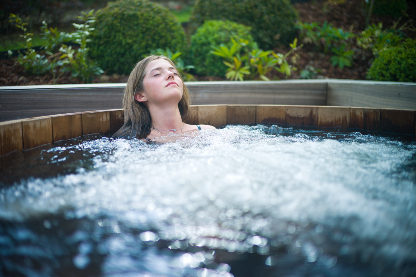 Girl relaxing in a cedar wooden hot tub